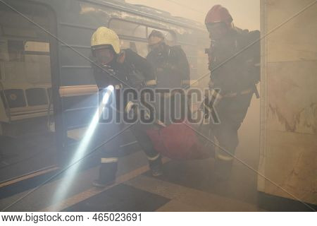 The Concept Of The Rescue Service. Rescuers-firefighters Evacuate On A Stretcher The Victim Of A Fir