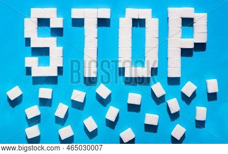 The Word Stop From Cubes Of Sugar. Diabettes Kills. Blue Background. Concept Caries.