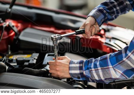 Female Auto Mechanic Unscrewing A Nut To Replace A Car Spark Plug.