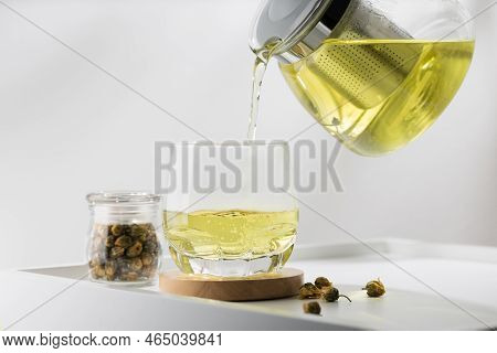 Pouring Chrysanthemum Tea Into Glass On The White Table