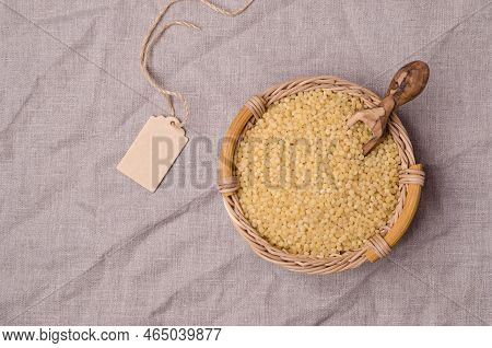 Traditional Dry Pearl Couscous In A Wicker Basket On A Textile Background. Top View.