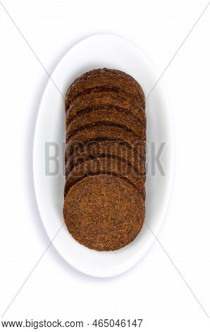 Pumpernickel Slices In A White Bowl. Circle Shaped Disks Of A Heavy, Slightly Sweet, Dark Brown Rye 