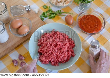 Close Up On Human Hands Preparing  Meatballs With Raw Materials To Mix, Home Kitchen And Yellow Tabl