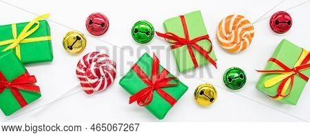 Banner Happy Holidays: Gifts With Lollipops And Red, Green, Golden Bells On A White Background. The 