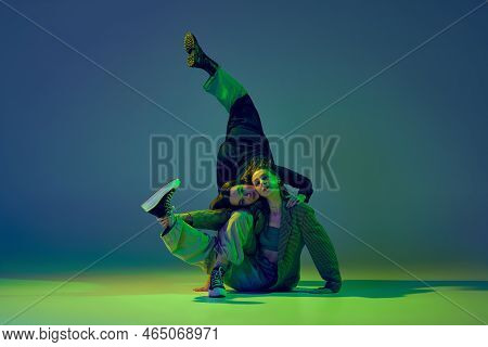 Modern Dance Concept. Energetic Couple Of Two Young Woman Dancing Contemporary Dance On Gradient Blu
