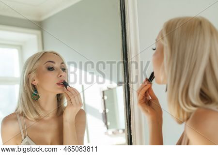Beautiful Blonde Woman Is Applying Lipsick Make Up And Looking To The Mirror