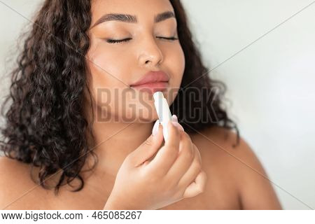 Lip Care Concept. Beautiful African American Plus Size Woman Using Chapstick To Moisturise Her Plump