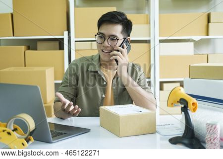 Young Male Small Business Enrtrepreneur, Online Store Owner Working On Laptop With Boxes On Desk At 
