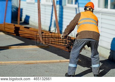 Slinger Stacks Thin Metal Pipes In Stack On Construction Site. Close-up. Real Workflow. Unloading Of