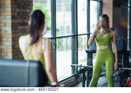 Asian Woman Beaultiful Building Slim Body In Green Sportswear With Smartphone Taking Mirror Selfie I