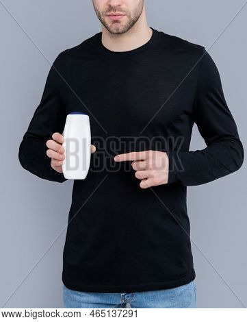 Handsome Man Point Finger On Bottle Of Unbranded Cosmetic. Man Hold Unbranded Cosmetics