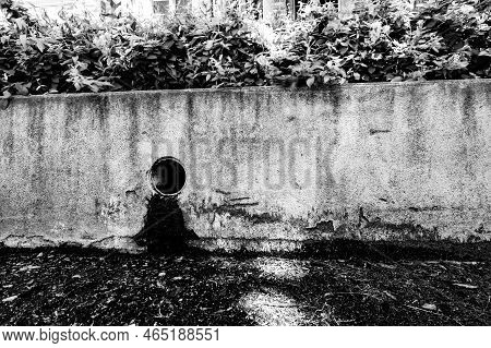 Stormwater Drain Outlet In An Urban Area With Seepage Discoloring A Concrete Barrier