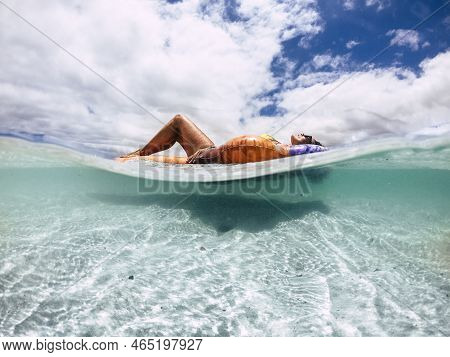 Beautiful Tanned Young Woman Lay Down And Relax On A Trendy Inflatable Lilo In A Paradise Beach With