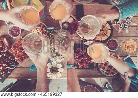 Above View Of People Clinking And Toasting Together To Celebrate Before Lunch - Wooden Table Full Of
