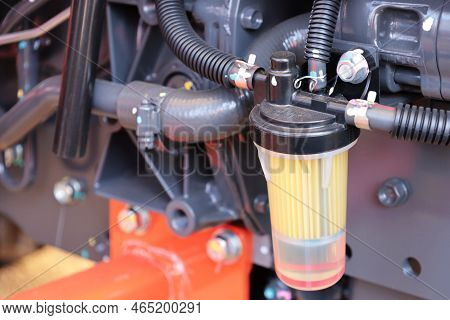 Tractor Fuel Filter. Transparent Fuel Filter With Black Rubber Hose Mounted On Tractor Side With Cop