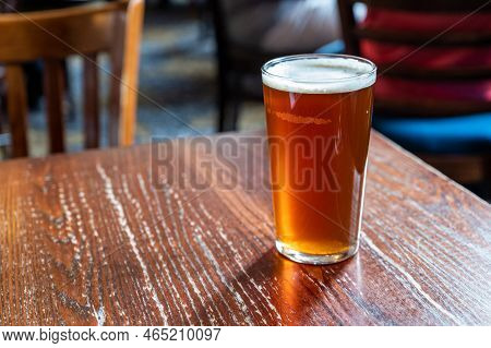 Pint Glass Of British Golden Ale Or Ipa Beer Served In Old Vintage English Pub, Close Up