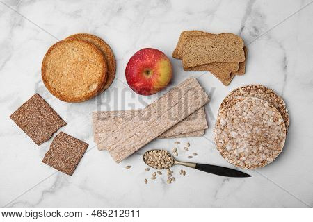 Rye Crispbreads, Rice Cakes And Rusks On White Marble Table, Flat Lay