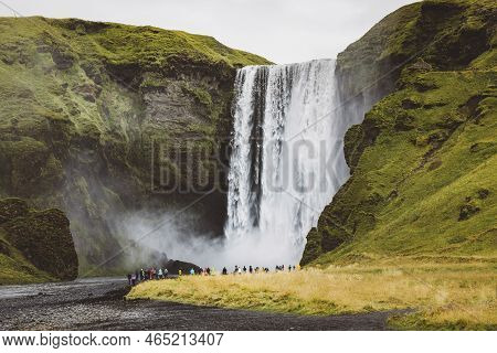 Famous Skogafoss Waterfall On Skoga River - Tourists Standing In Front And Watching Waterfall