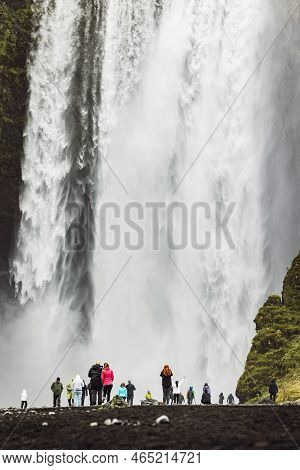 Tourists Standing Under Skogafoss Waterfall - Close Up Vertical Shot