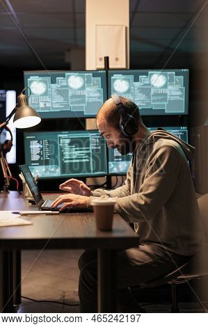Cyber Criminal Trying To Hack Computer Server, Wearing Headphones And Working Late At Night. Hacker 