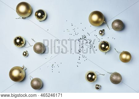 Some Gold Christmas Balls And Confes On A White Surface With Scattered Confectional Objects In The B