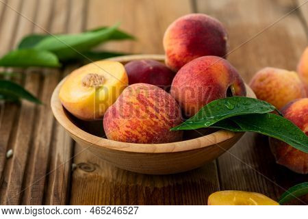 Peaches With Leaves In A Wooden Bowl With Peach In Halves On Top. Flat Lay Composition With Ripe Jui