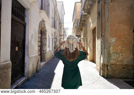 Holidays In Calabria, Italy. Back View Of Beautiful Stylish Tourist Girl Walking Between Narrow Alle