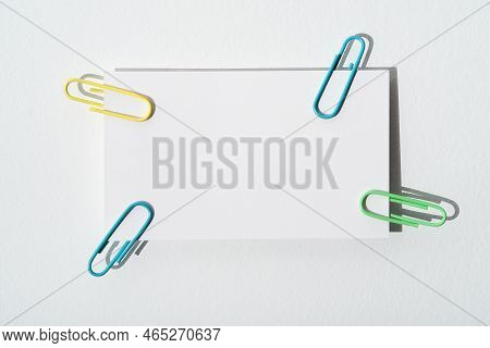 Close-up White Sheet With Copy Space Attached Paper Clips. Business Card With Colorful Paper Clips O