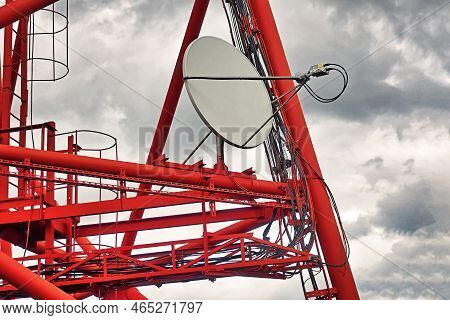 Part Of Communication Tower With Satellite Dish Against Backdrop Of Dramatic Sky With Storm Clouds.