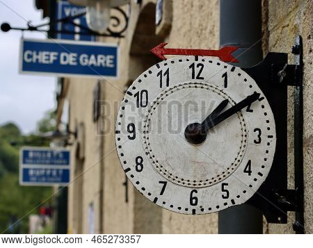 Historic Steam Train Station In Fond-de-gras, Luxembourg. White Clock Face With Red Arrow Pointing T