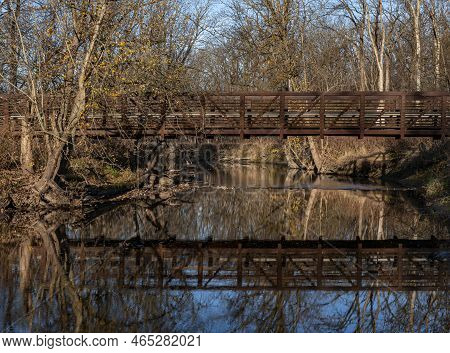 A Footbridge Over The Waters Of Hickory Creek Shows The Waning Autumn Leaves On The Trees, Hickory C