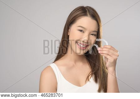 Young Smiling Woman Holding Invisalign Braces Over White Background Studio, Dental Healthcare And Or