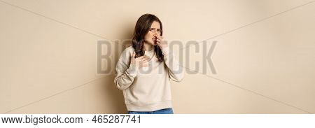 Woman Expressing Disgust Of Bad Disgusting Smell, Close Nose And Grimaing From Dislike, Standing Ove