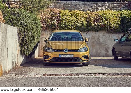 Pula, Croatia - Circa 2022: Golden Volkswagen Golf Car Parked In Front Of A Luxury Property