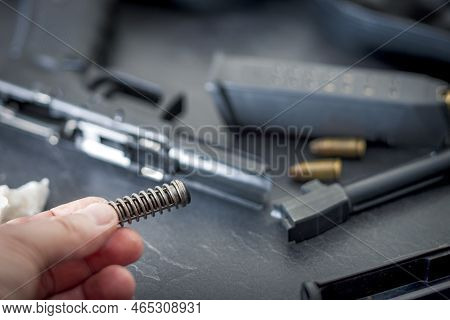 Closeup Of Disassembled Pistol And A Hand Holding Recoil Spring