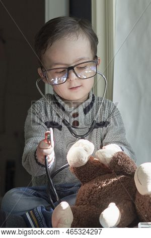 A Little Boy Playing With A Stuffed Bear And Stel In Front Of The Childs Eyeglasses