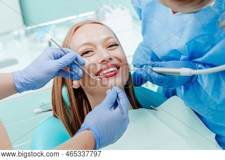 Attractive Young Woman Smilling With Natural White Teeth In Dental Clinic. Hands Doctor Dentist With