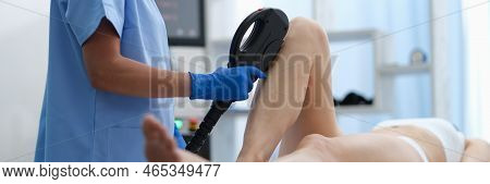 Doctor Hands In Blue Medical Gloves Hold Depilatory Machine And Use It On Woman Legs. Laser Hair Rem