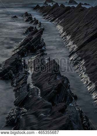 Abstract Landscape Image Of Rocks On Welcome Mouth Beach At Sunset With Tide Marks On Rocks Reflecti