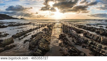 Stunning Sunset Landscape Image Of Welcome Mouth Beach In Devon England With Beautiful Rock Formatio