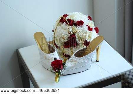 A Pair Of White Women's High Heels And A Beautiful Rose Flower Bucket.