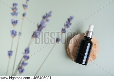 Cosmetic Bottle With Pipette On Wooden Slice  Top View, Flat Lay On Colored Background With Lavender