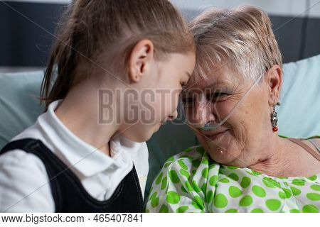 Family Members Smiling Happily At Sanatorium Nursing Home. Girl Showing Affection To Elderly Patient