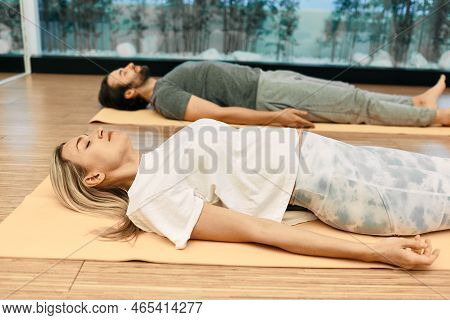 Shavasana. Man With Woman Wearing In Sportswear Practice Yoga While Lying Down In Savasana Or Corpse