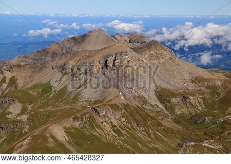 Close-up View Of The Landscape With Mountain Peak In The Foreground Against A Blue Sky With Clouds O