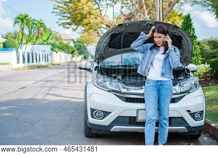 Angry Asian Woman And Using Mobile Phone Calling For Assistance After A Car Breakdown On Street. Con