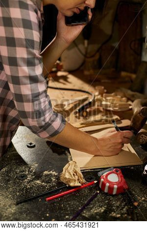 Cheerful Carpenter Woman Discussing Order Details With Her Customer On Smartphone
