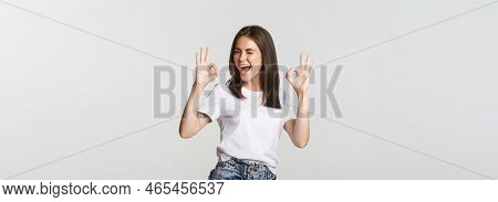 Satisfied Cheerful Brunette Girl Winking Sassy And Showing Okay Gesture In Approval