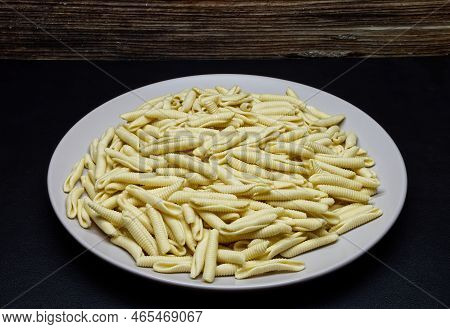 Uncooked Italian Maccheroni Al Pettine Pasta On Black Background.