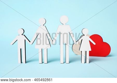 Figures Of Family Stainding Near Heart And Coins On Light Blue Background. Insurance Concept